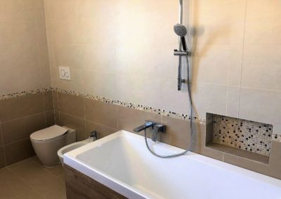 Bagno padronale con piastrelle in gres e fascia decoro a mosaico